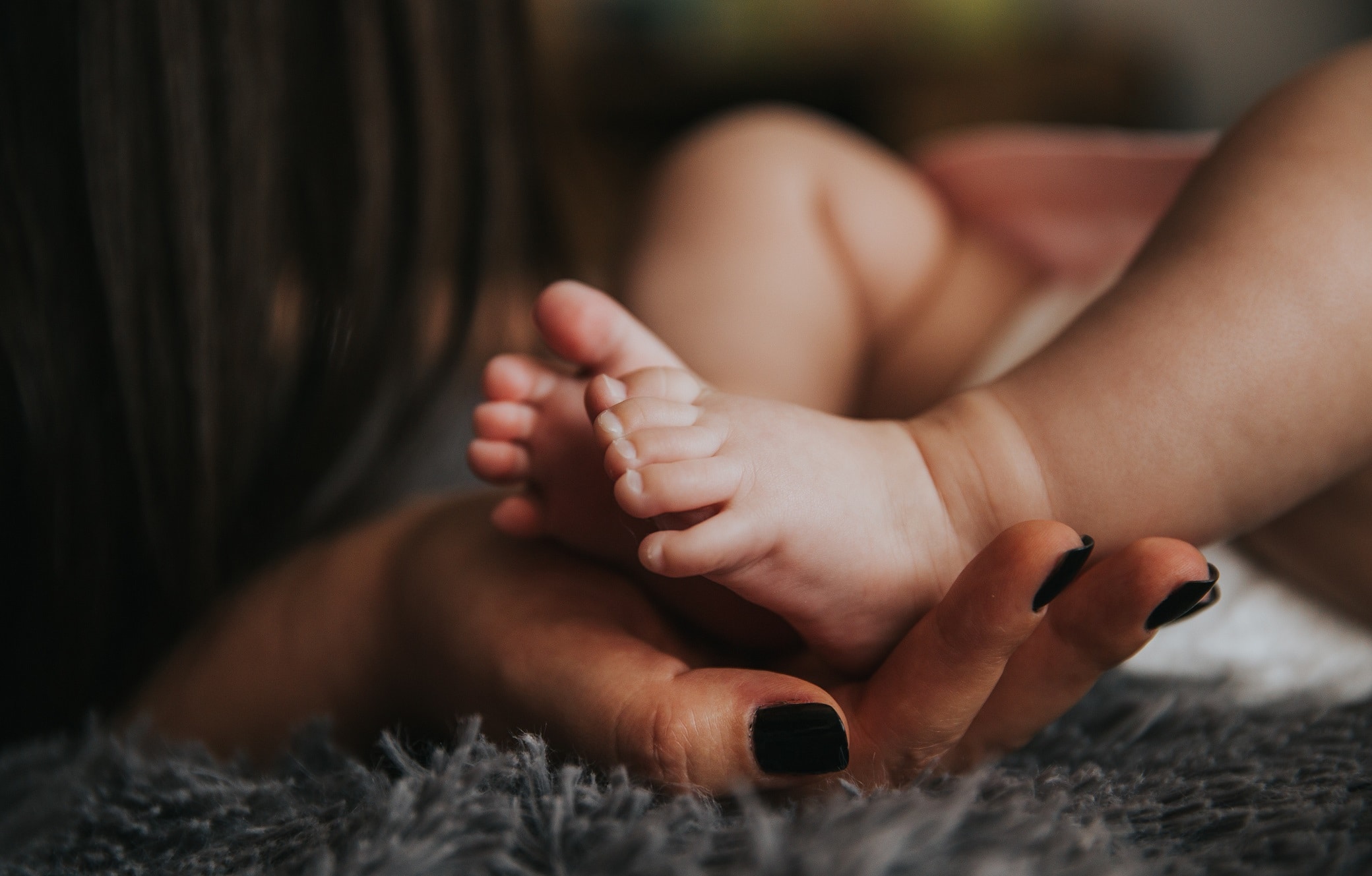 Close-up of baby feet held in mother's hand